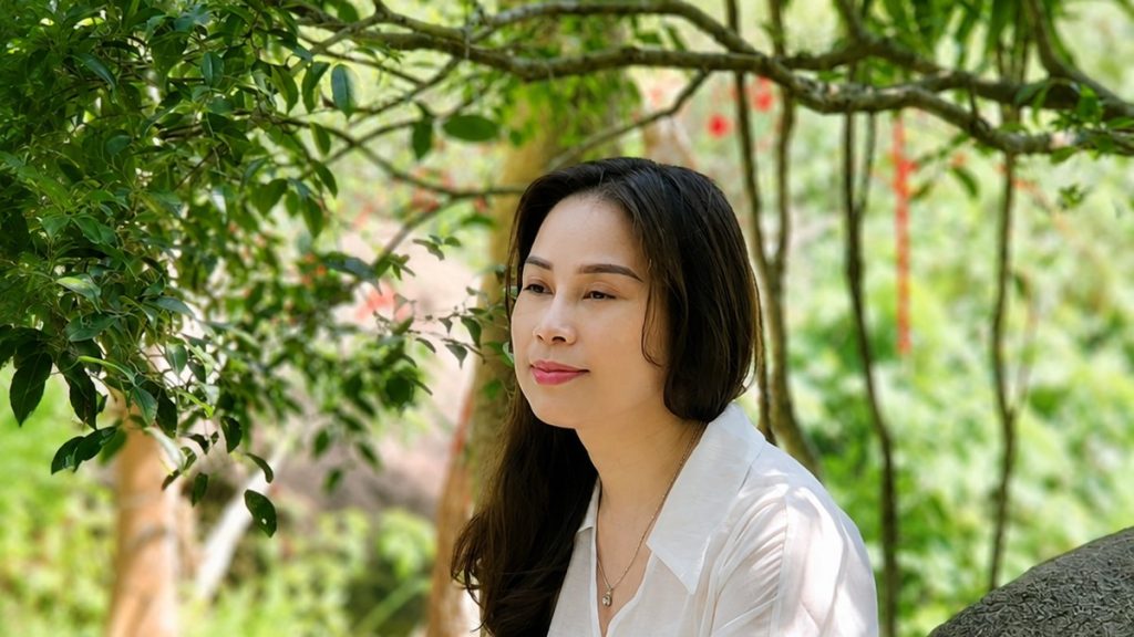 Nhà tâm lý Nguyễn Tú Oanh ngồi bên giàn hoa, chủ đề chồng ngoại tình nên làm gì