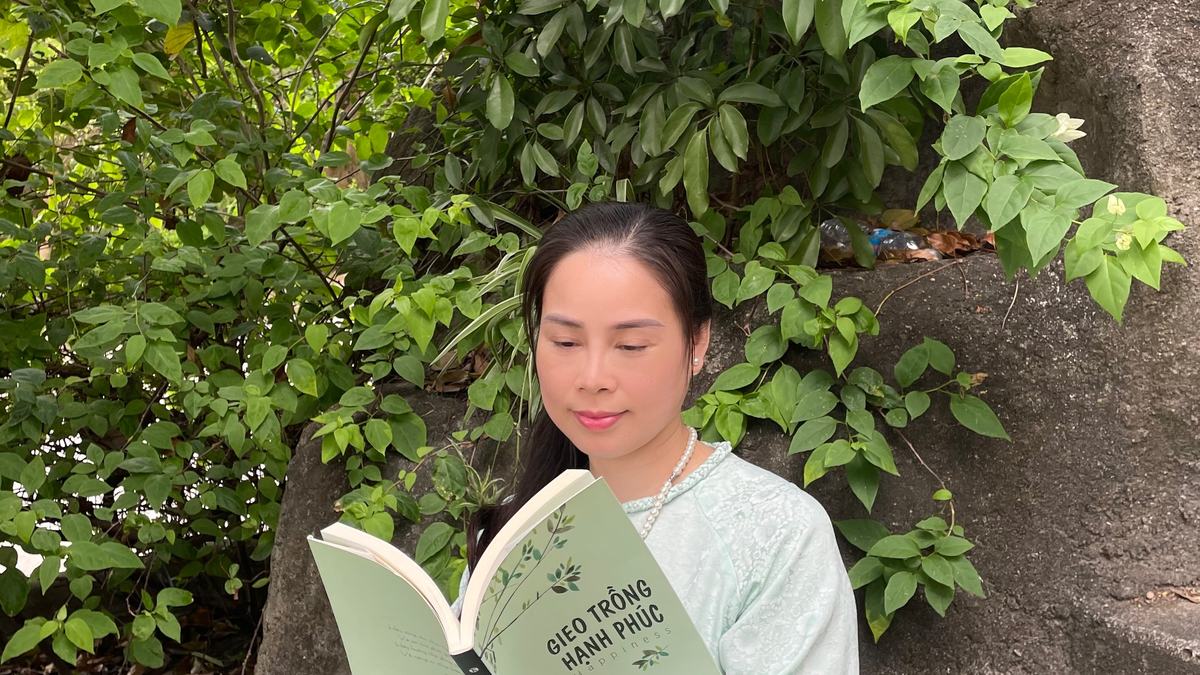 Nguyễn Tú Oanh ngồi ghế đọc sách trong nhà
